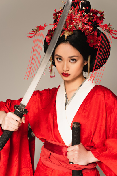 Pretty asian woman in red costume holding sword isolated on grey  - Фото, изображение