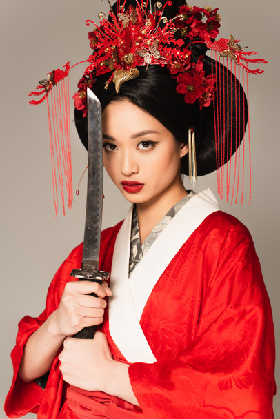 Brunette japanese woman posing with sword isolated on grey  - Fotó, kép