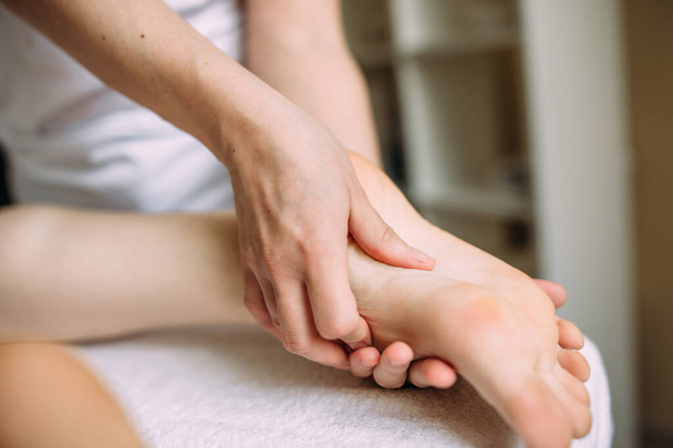 El masajista da un masaje a los pies femeninos en el spa. - Foto, imagen