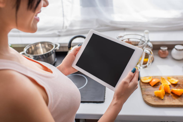 partial view of happy blurred woman using digital tablet in kitchen  - Фото, изображение