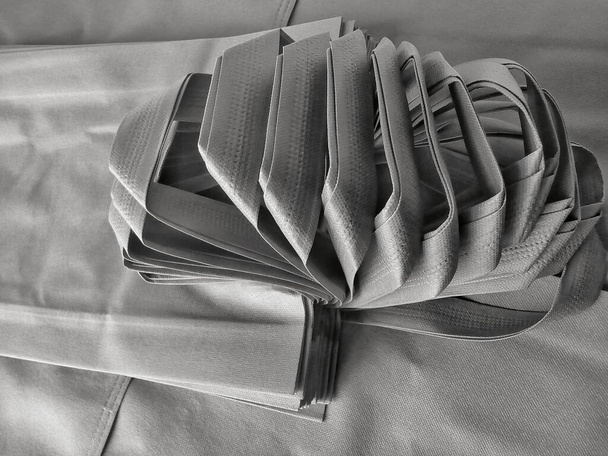 Μη υφαντό λουράκι. ένα σύνολο από στοιβαγμένες γκρι σακούλες σχοινί πολυπροπυλενίου tote - Φωτογραφία, εικόνα