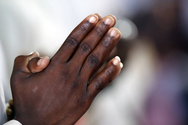 Afrikaanse kerk. Zondag katholieke mis. Een biddende man. Een close-up van handen. Agbonou Koeroma. Togo.  - Foto, afbeelding