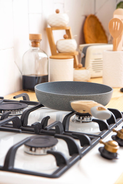 Ceramic frying pan stands on the stove on the kitchen in the morning - Photo, Image
