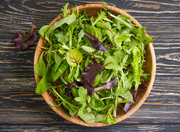 зелене листя салату в тарілці на дерев'яному фоні
 - Фото, зображення