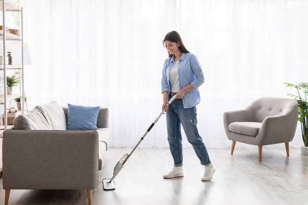 Portret uśmiechniętej kobiety sprzątającej podłogę mopem natryskowym - Zdjęcie, obraz