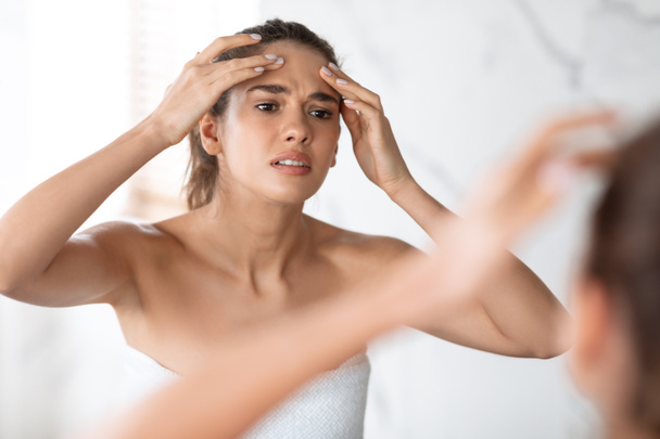 Frustrated Lady Squeezing Pimple On Forehead In Modern Bathroom Indoors - Fotó, kép