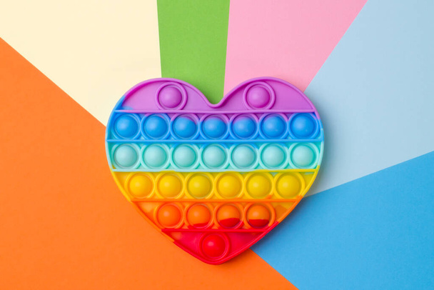 Силіконова веселка серцева іграшка на барвистому різнокольоровому фоні
. - Фото, зображення