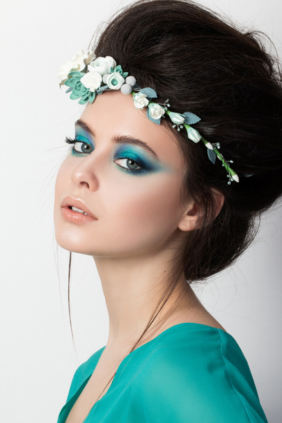 Portrait of young brunette girl in turquoise dress with flower d - Fotografie, Obrázek