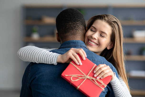 Портрет счастливой молодой женщины, получившей романтический подарок от своего чёрного парня - Фото, изображение