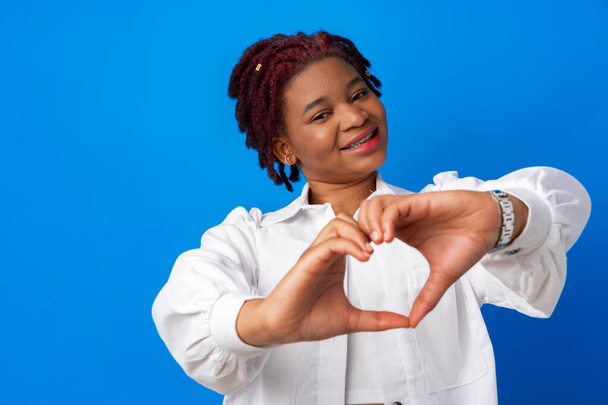 Nice afro woman put hands in heart shape against blue background - Фото, зображення