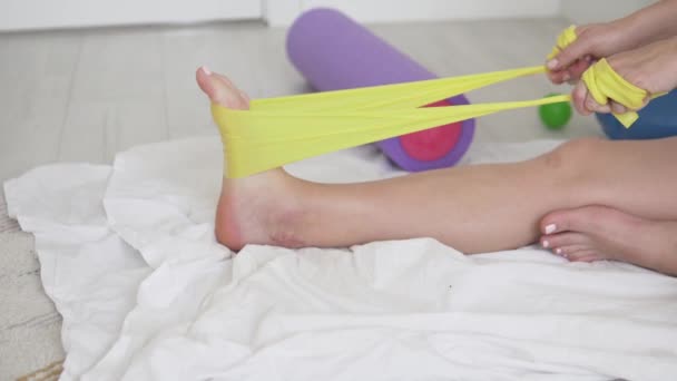 Une femme fait de la gymnastique pendant la réadaptation après une blessure au tendon d'achilles - Séquence, vidéo