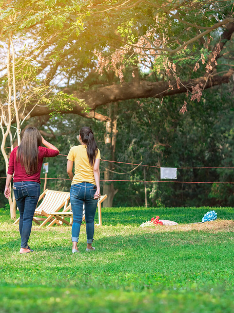 Back view of Asian woman with friends walking together on lawn through green garden.Female relaxing in park. Happiness friends spending time together outside in green nature. Enjoying nature outdoors. - Photo, Image