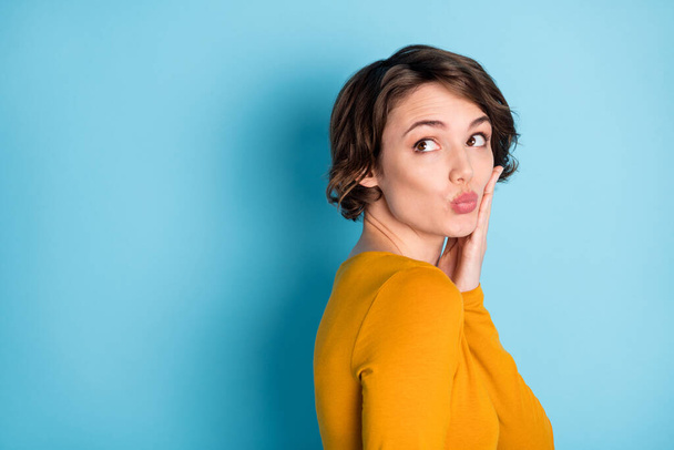Profile portrait of nice optimistic brunette lady blow kiss look empty space wear yellow shirt isolated in vivid blue color background - Foto, Bild
