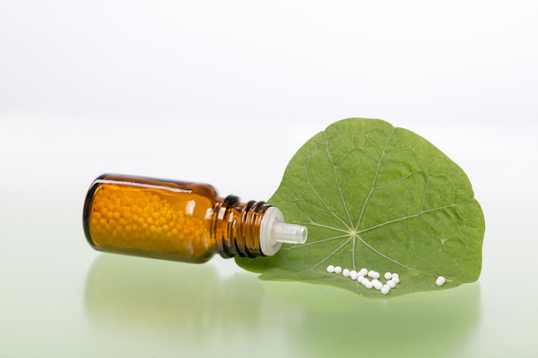 bottle with homeopathy globules and green leaf - Photo, Image