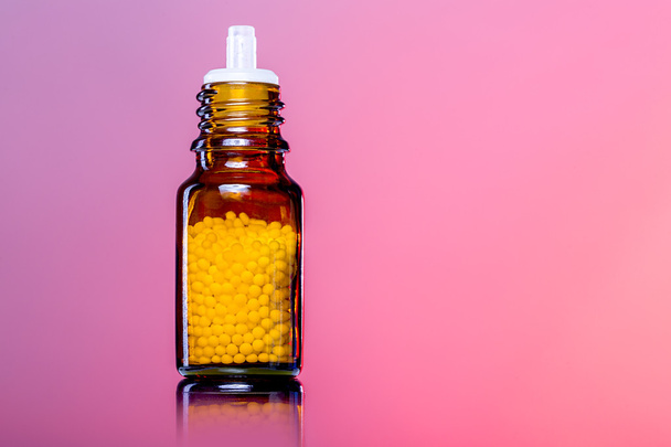Einzelflaschen mit Homöopathie-Kügelchen, weiß-roter Hintergrund - Foto, Bild