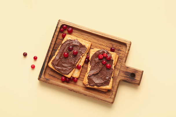 Tasty crackers with chocolate paste and cranberry on color background - Photo, Image