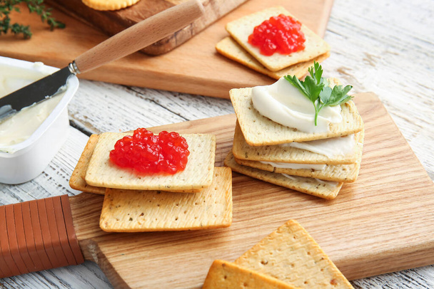 Leckere Cracker mit Käse und rotem Kaviar auf hellem Holzgrund, Nahaufnahme - Foto, Bild