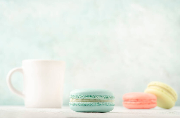 colorful macaroons and cup of coffee on table over green background with copy space - Fotografie, Obrázek