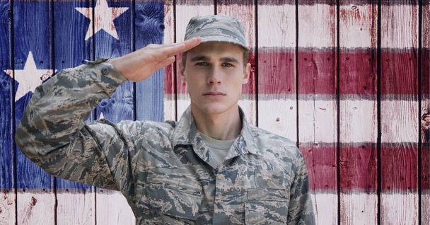 Composition of male soldier saluting over american flag. american patriotism, independence and celebration concept digitally generated image. - Foto, Imagem