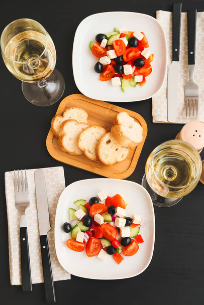 Πιάτα με φρέσκια ελληνική σαλάτα και ποτήρια κρασί στο τραπέζι στο εστιατόριο - Φωτογραφία, εικόνα