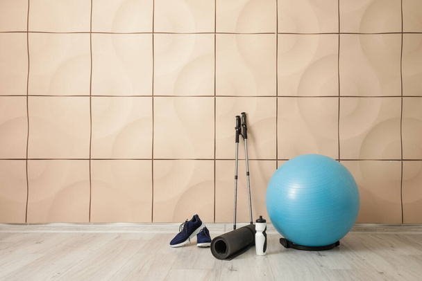 Conjunto de equipamentos esportivos com bola de fitness e sapatos perto da parede de cor - Foto, Imagem