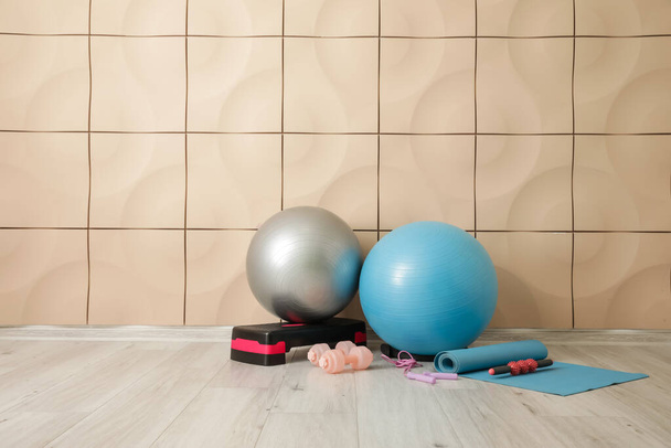 Комплект спортивного инвентаря с мячами рядом с цветной стеной - Фото, изображение