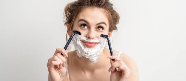Beautiful young caucasian smiling woman shaving her face with razor looking up on white background - Foto, imagen