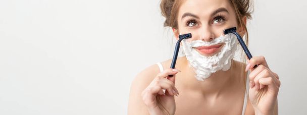 Gyönyörű fiatal fehér mosolygós nő borotválkozás arcát borotvával néz fel a fehér háttér - Fotó, kép