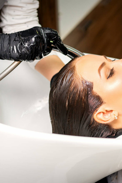 美容室でヘアスタイルを作る前に、女性のクライアントにシンクで髪を洗う男性の美容師 - 写真・画像