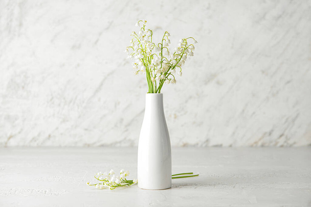 Βάζο με όμορφα λουλούδια κρίνου της κοιλάδας στο φως φόντο - Φωτογραφία, εικόνα