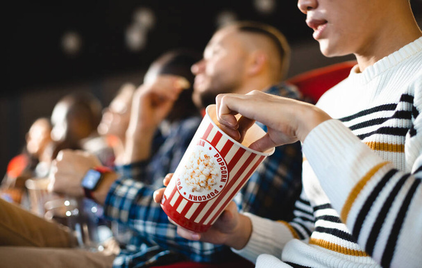 Friends are watching a movie in the cinema with popcorn. People sit in the armchairs of the cinema and look at the screen - Φωτογραφία, εικόνα