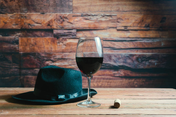 glass of red wine next to cork and fedora hat in cava - Photo, Image