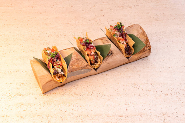 Presentation of three tacos in a wooden log with cavities to hold the fried corn flour tortillas - Foto, afbeelding
