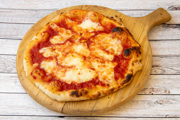 Pizza margarita in the purest Italian style with mozzarella cheese on wooden board - Foto, Bild