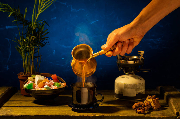 Despeje café fabricado a partir de café turco acabado de fazer. Despeje café em uma caneca. Mão e turca para o café. Vista frontal. - Foto, Imagem
