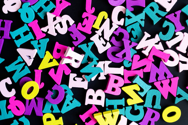 Letras coloridas del alfabeto inglés de madera vista superior sobre fondo negro - Foto, Imagen