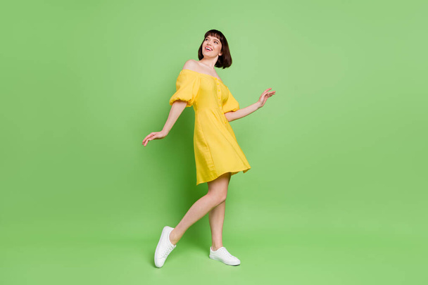 Full body photo of cheerful young happy lady look empty space dance isolated on bright green color background - Foto, Imagen