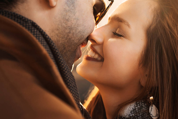 Γκρο πλαϊνή άποψη της όμορφης γυναίκας με κόκκινα μαλλιά και απαλό μακιγιάζ φιλιά με το φίλο της με κλειστά μάτια - Φωτογραφία, εικόνα