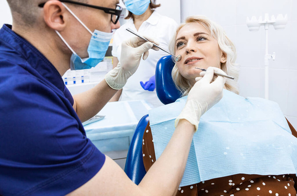 Dentistry concept. Professional dental services and modern equipment without pain. The doctor consults and treats the woman, conducts an examination and draws up a treatment plan - Foto, afbeelding