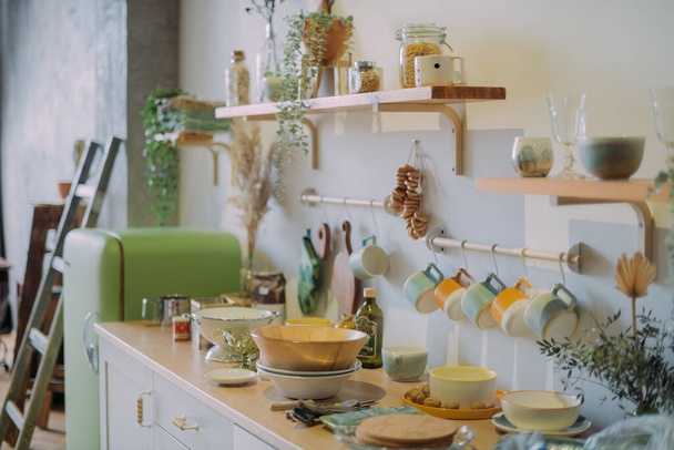 Moderne Küche im skandinavischen Landhausstil mit hellgrünen Tönen. Details Küche und Esstisch mit Frühstück, serviert in Keramikschalen - Foto, Bild