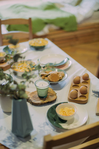 Details of a modern kitchen in a Scandinavian rustic style in light green shades. Served breakfast table with handmade ceramics, wooden cutting boards and kitchen accessories - Fotó, kép