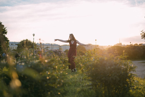 Kauniin nuoren naisen muotokuva puistossa auringonlaskun aikaan kesällä. Tyttö tanssii ja iloitsee illalla auringonlaskussa valo pioni pensaita - Valokuva, kuva