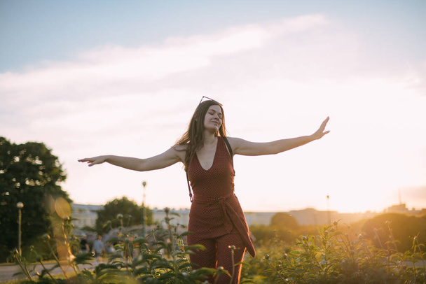 Portrét krásné mladé ženy v parku při západu slunce v létě. Dívka tančí a raduje se večer v zapadajícím slunci v pivoňském křoví - Fotografie, Obrázek