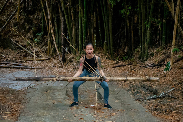 Mujer asiática levanta un bambú en un camino seco en Minca, Colombia - Foto, imagen