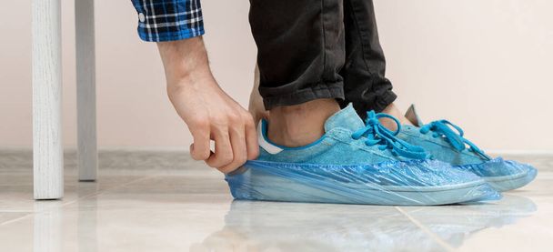 Hastanedeki kirli spor ayakkabılara mavi ayakkabı kılıfları takan insanlar. - Fotoğraf, Görsel