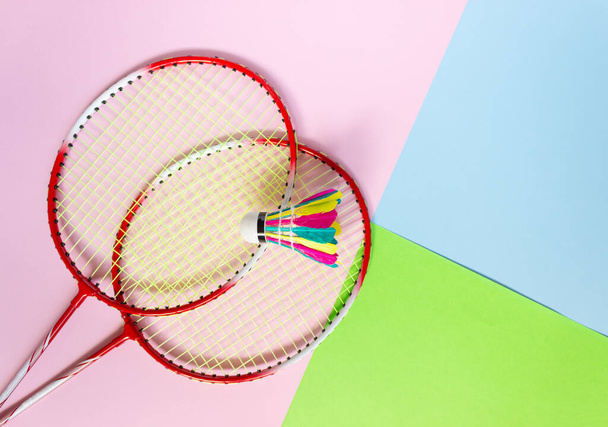 Raquetas y una lanzadera de bádminton en un fondo multicolor, vista superior. Deportes, actividades al aire libre de verano. - Foto, imagen