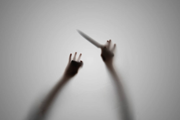 sötét sziluett egy sötét ember kezében egy kés, rémálom horror koncepció, a fókusz elmosódott - Fotó, kép