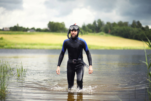 A scuba diver in a wet suit prepares to immerse in a pon - Photo, Image