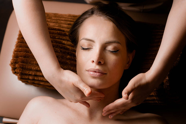 Masaje de cuello y cara en el spa. Masajista está haciendo tratamientos de belleza facial para un modelo femenino atractivo. Relajación - Foto, Imagen