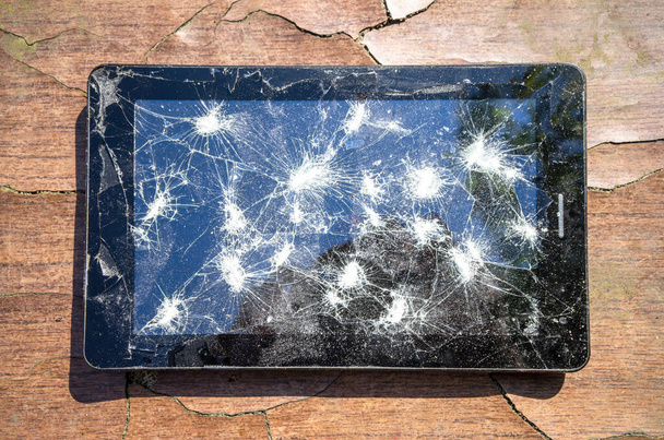 Czarna elektroniczna tabletka z zepsutym ekranem na popękanym drewnianym stole - Zdjęcie, obraz